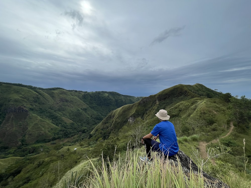 a man sitting on top of a lush green hillside