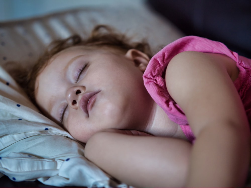 a little girl sleeping on a bed with her eyes closed