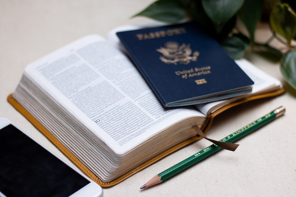 a passport, a cell phone, and a pen on a table