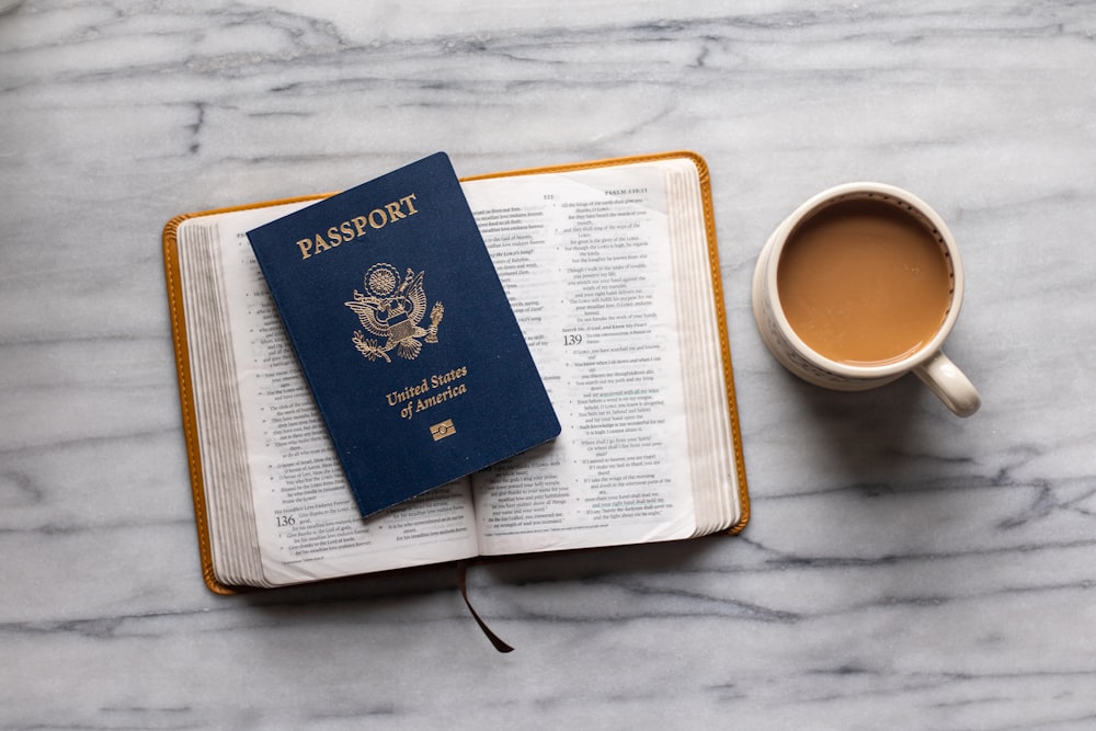 a passport sitting on top of a book next to a cup of coffee