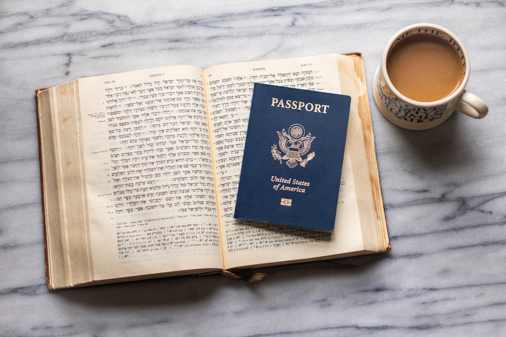 a passport sitting on top of a book next to a cup of coffee
