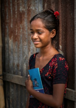 A young girl proudly holding her school books, symbolizing education and hope.