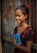 Smiling young female student holding a notebook, standing against a soft blue background.