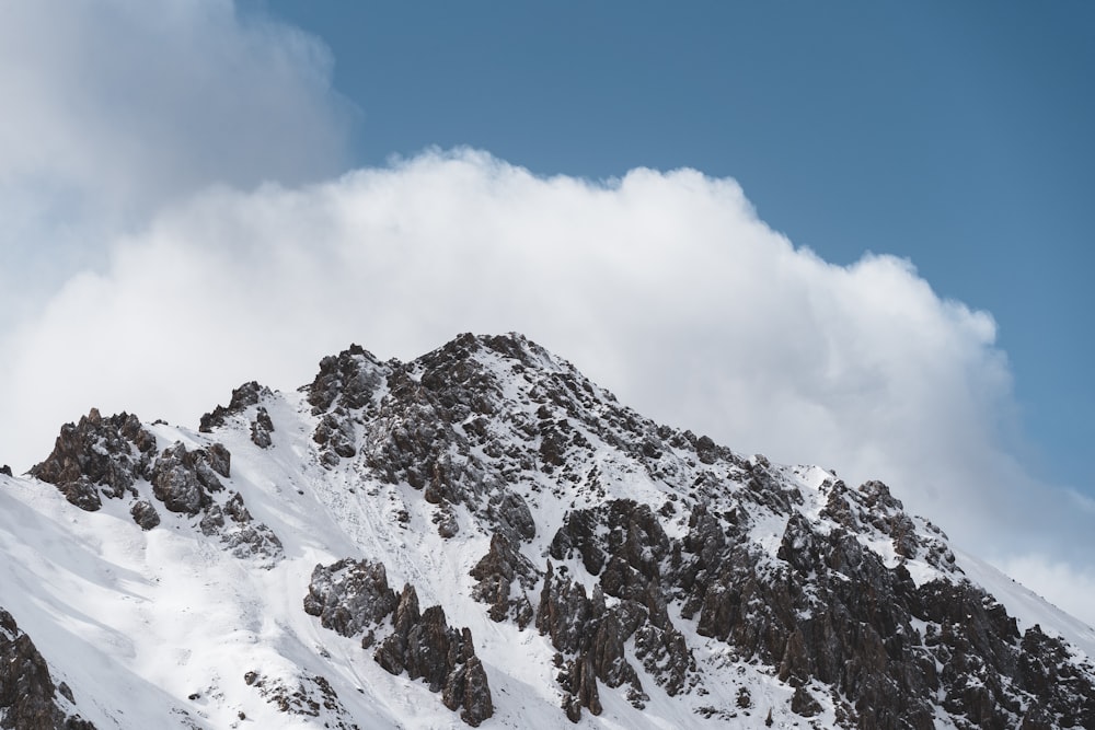 a snow covered mountain under a cloudy blue sky