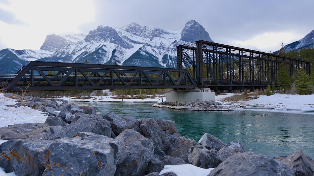 a bridge over a river with mountains in the background