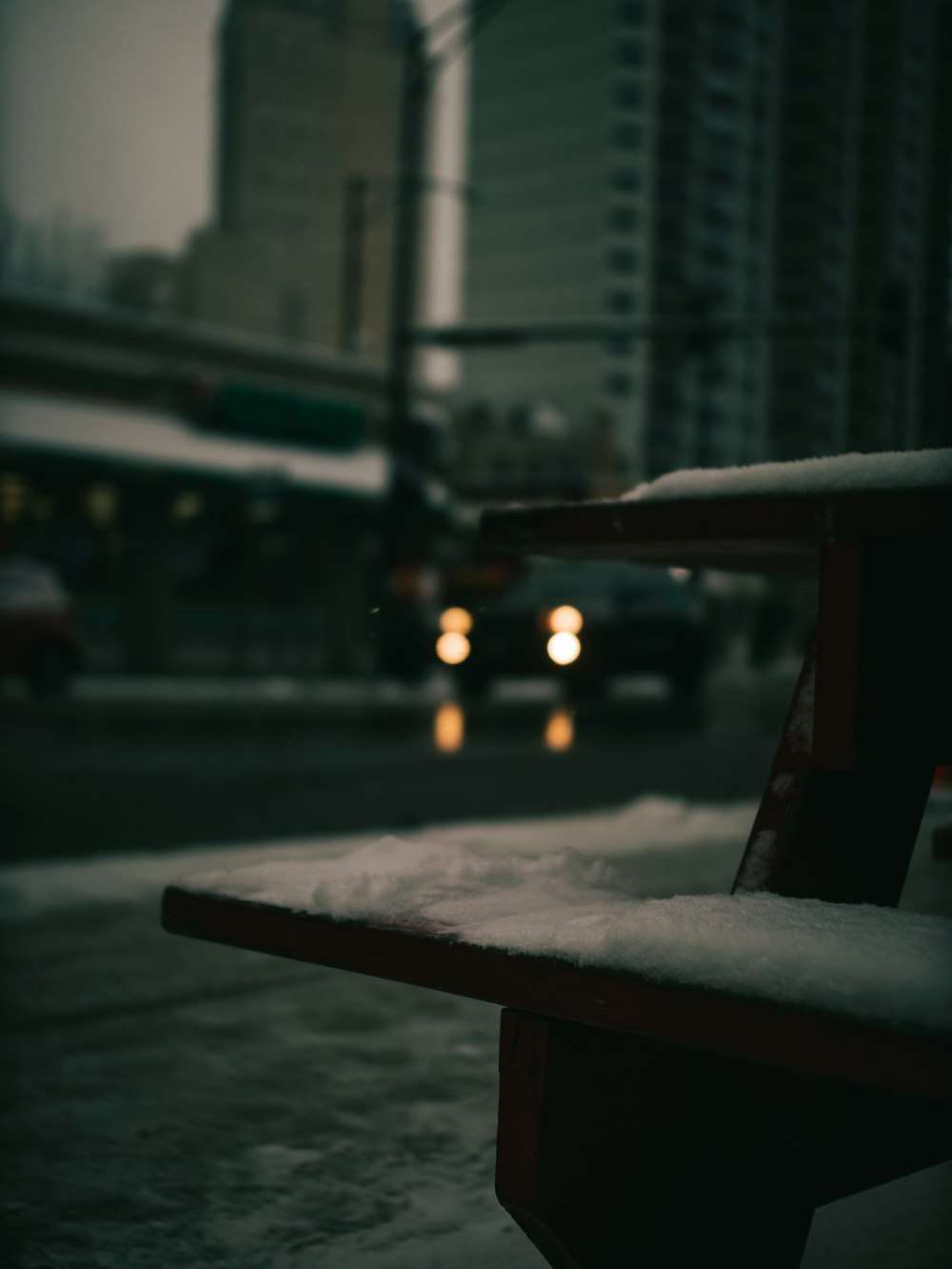 a bench on a city street covered in snow