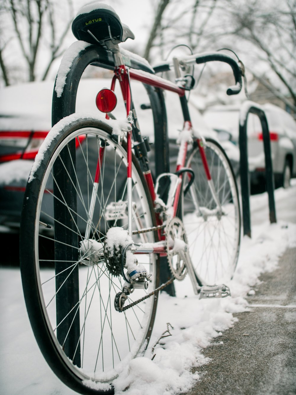 a red bicycle parked next to a parking meter covered in snow