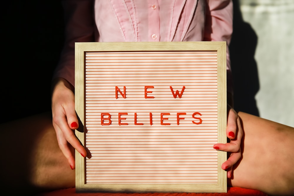 a woman holding a sign that says new belies