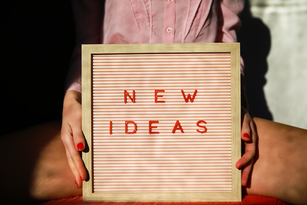 a person holding a sign that says new ideas