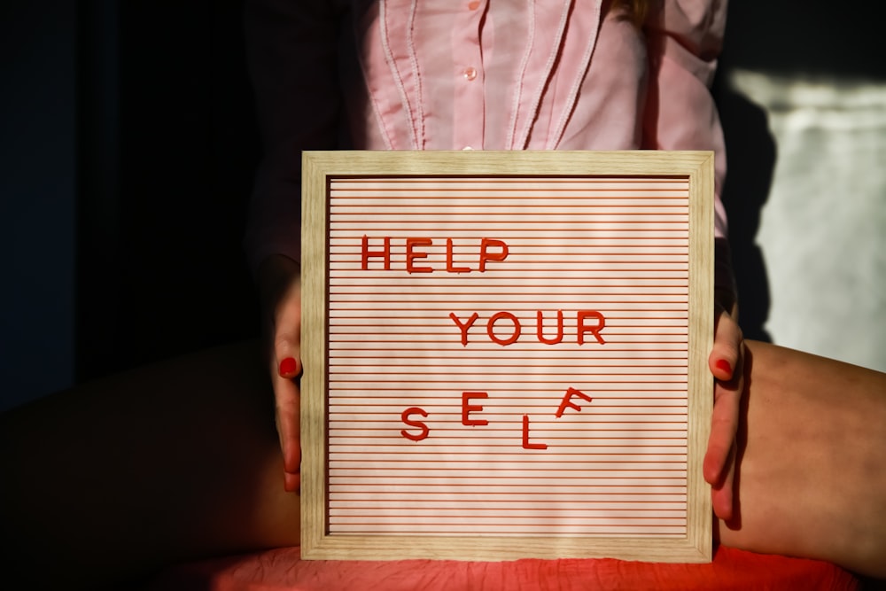 a person holding a sign that says help your self