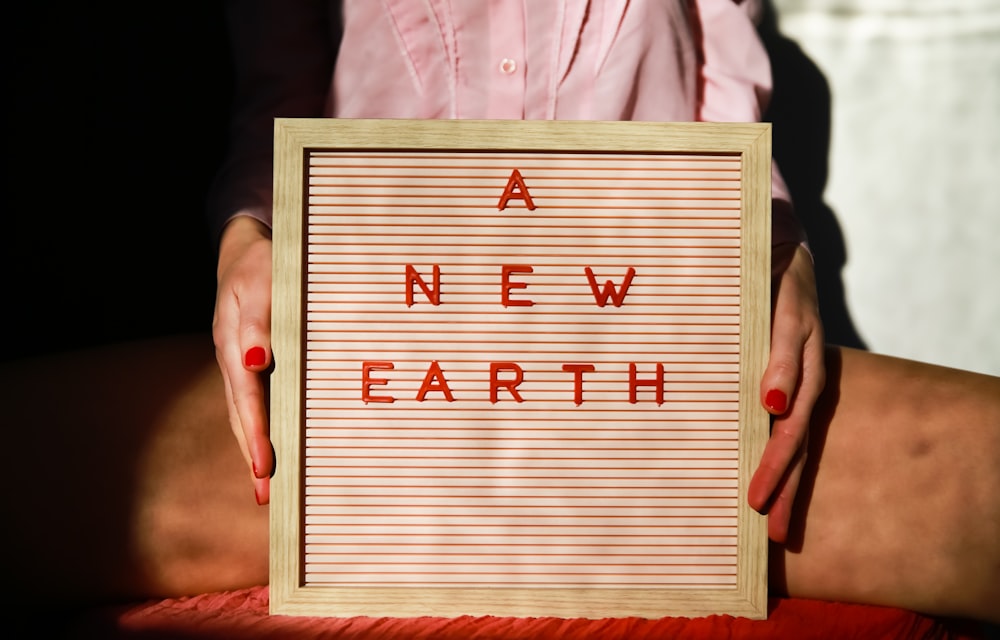 a woman holding a sign that says a new earth