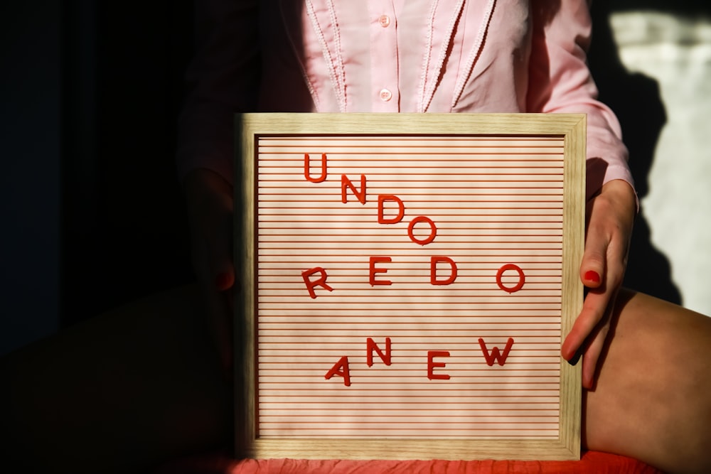a person holding a sign that says undoo redo new