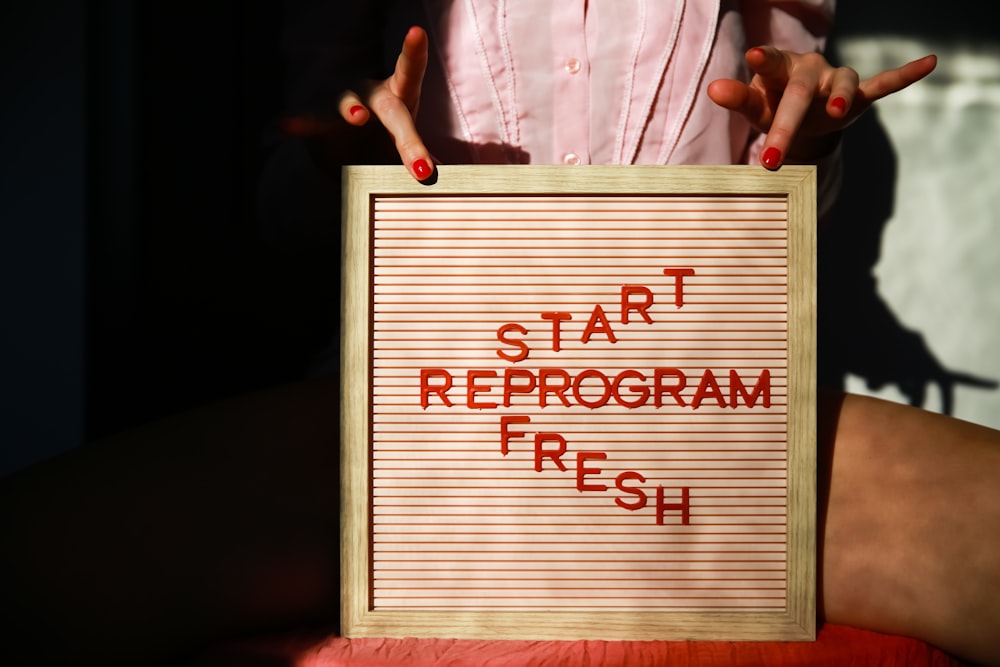 a person holding a sign that says start reprogram fresh