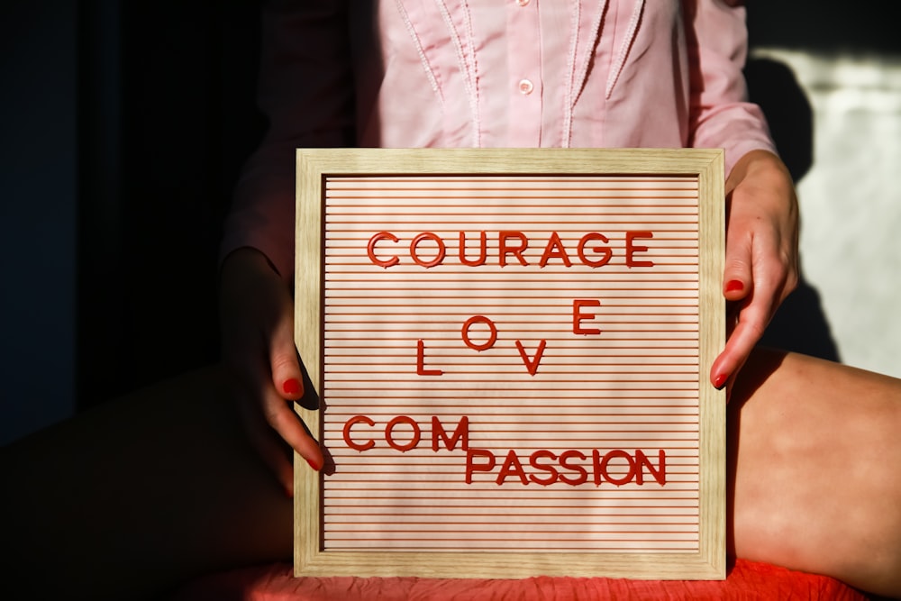 a woman holding a sign that says, courage love com passion
