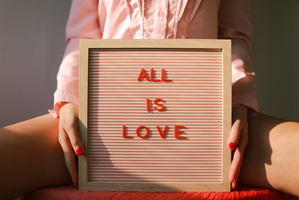 a woman holding a sign that says all is love