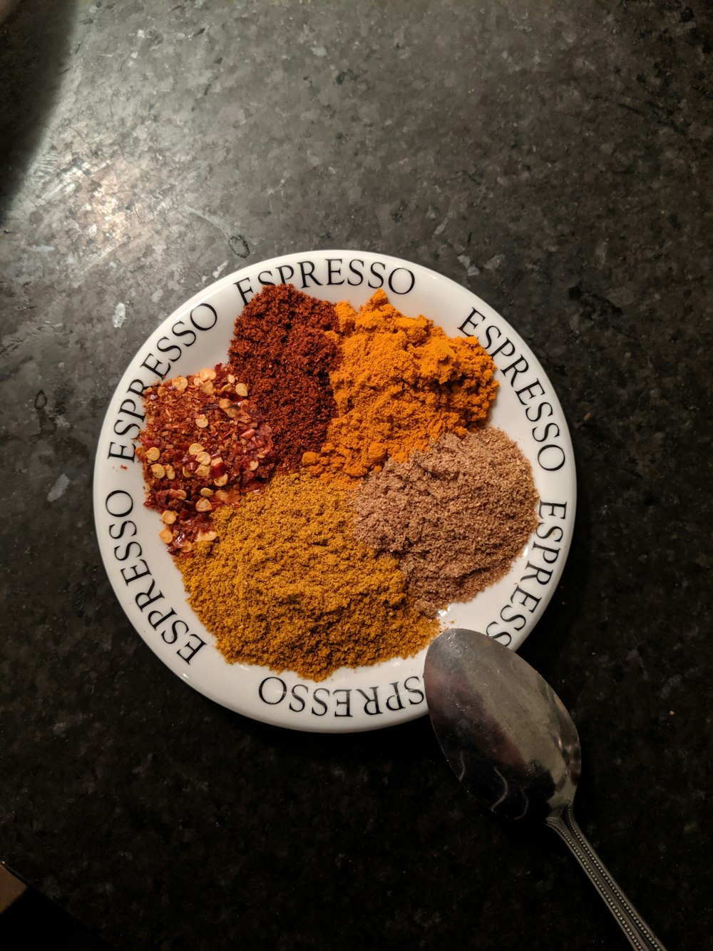 a plate of spices on a table with a spoon