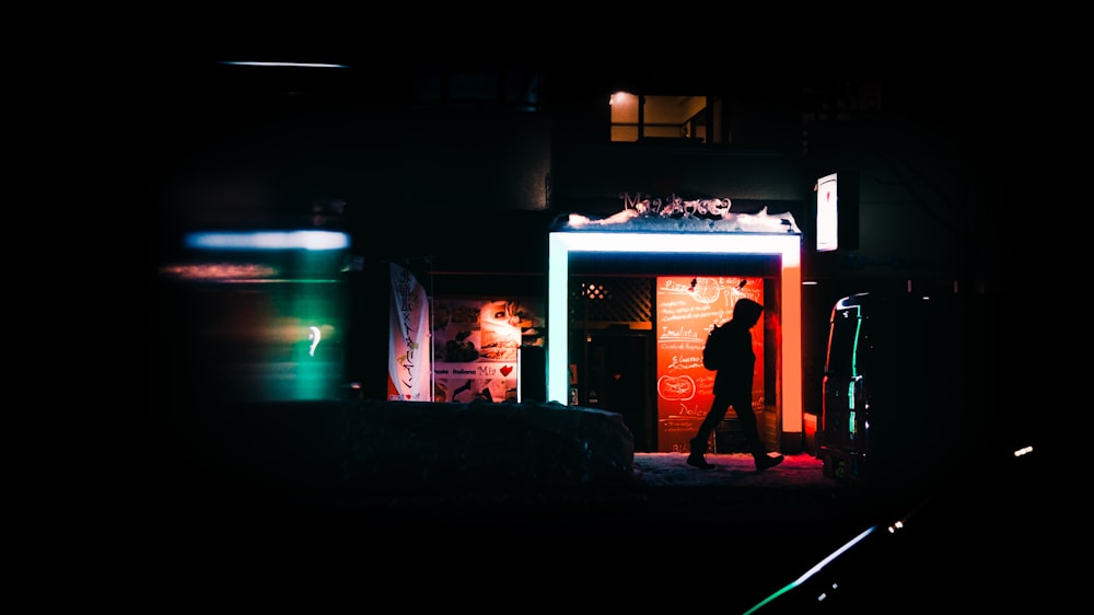 a couple of people standing outside of a building at night