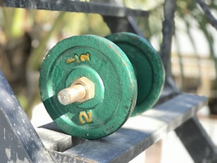 a green dumbbell sitting on top of a metal bench