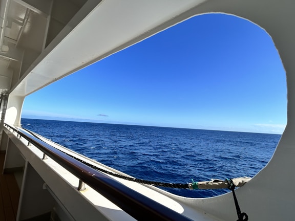 A panoramic view from the ship’s bow showing endless blue waves and a clear sky.