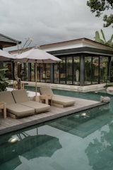 a pool with lounge chairs and umbrellas next to it