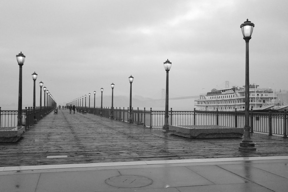 a pier with street lights and a cruise ship in the background