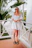 Smiling woman enjoying a sunny morning on a hotel balcony surrounded by tropical plants