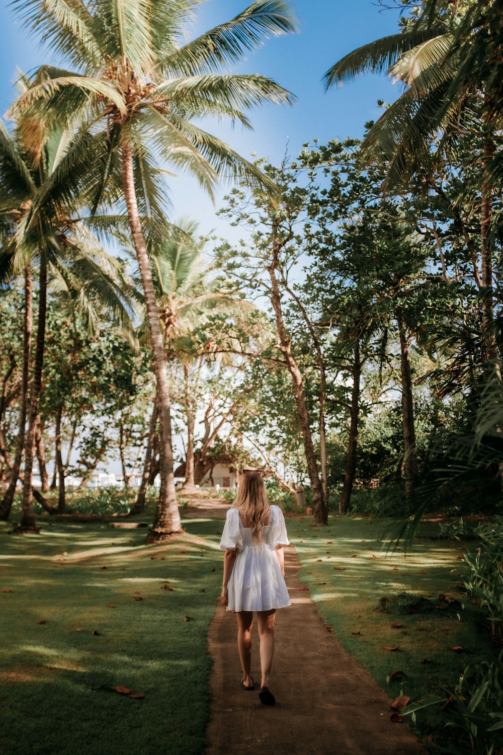 a woman in a white dress walking down a path