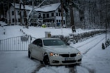 Professional driver opening car door for a passenger near a snowy chalet.
