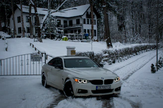 A modern home entrance with a solar-powered wireless parking barrier in action on a snowy day.