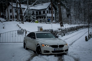 Professional driver opening car door for a passenger near a snowy chalet.
