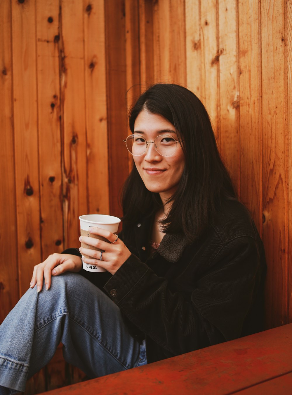 a woman sitting on a bench holding a cup of coffee