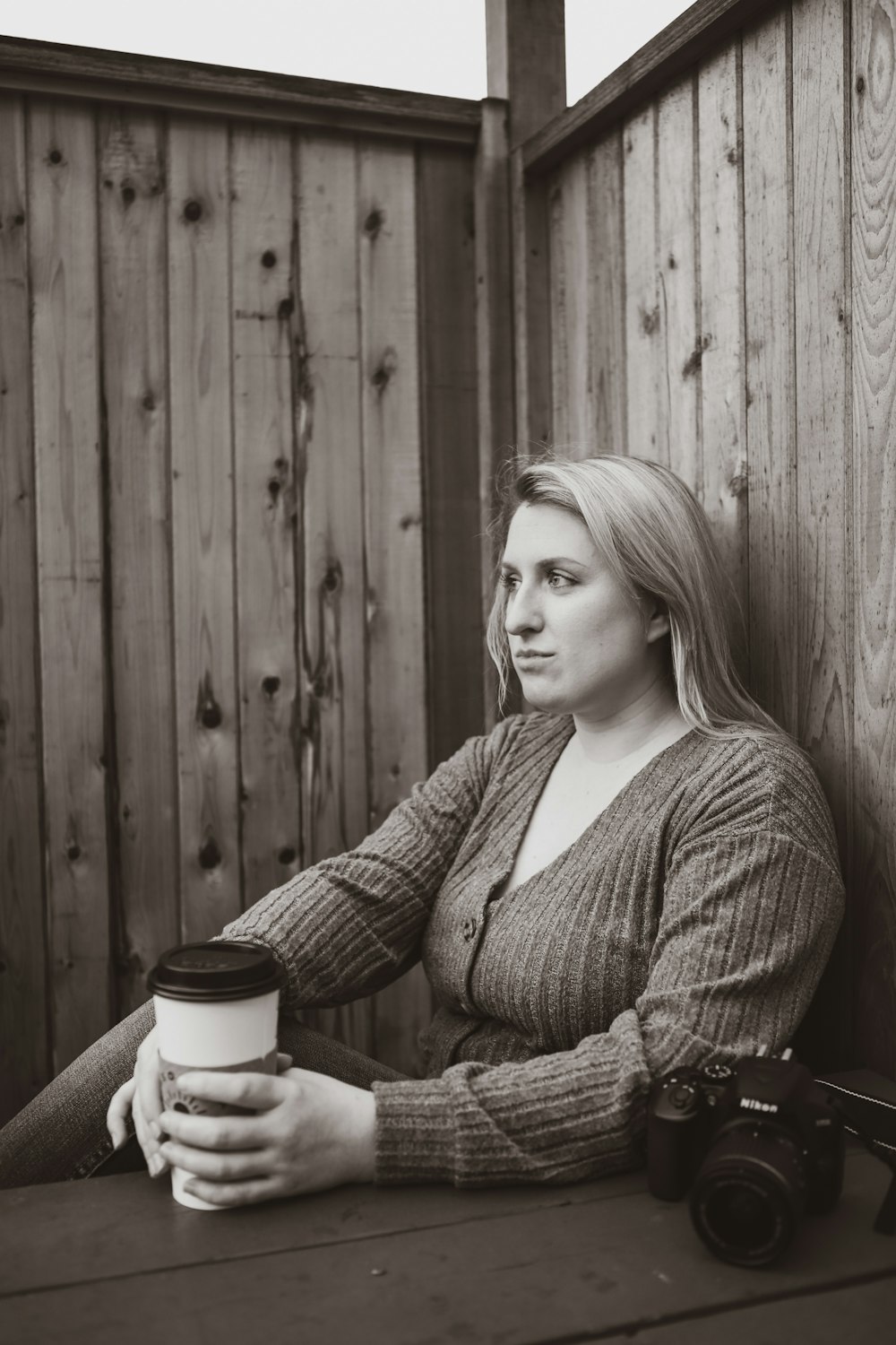 a woman sitting at a table with a cup of coffee