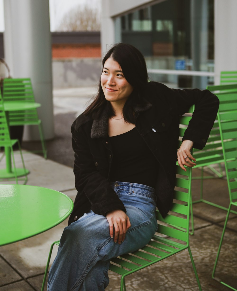 a woman sitting on top of a green bench