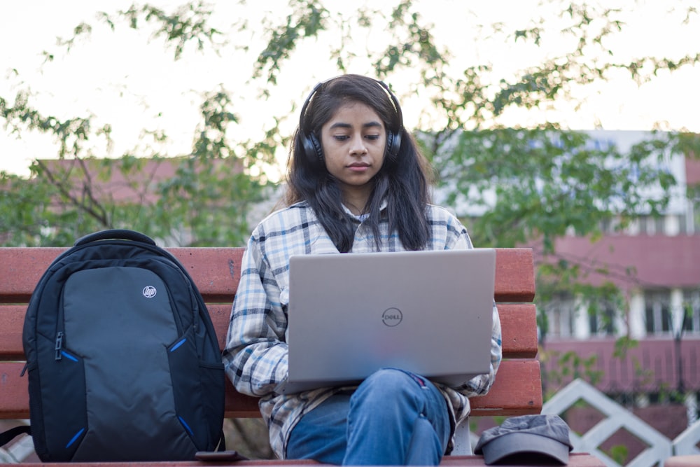 a woman sitting on a bench using a laptop computer