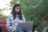 a woman sitting on a bench using a laptop computer