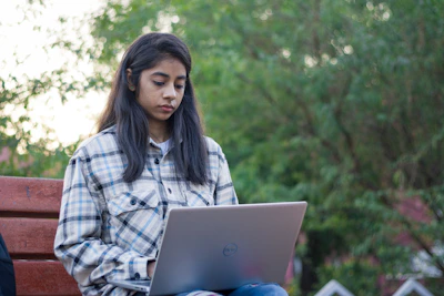 a woman sitting on a bench using a laptop computer