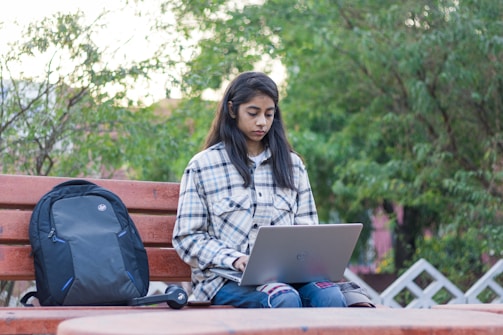 a woman sitting on a bench using a laptop