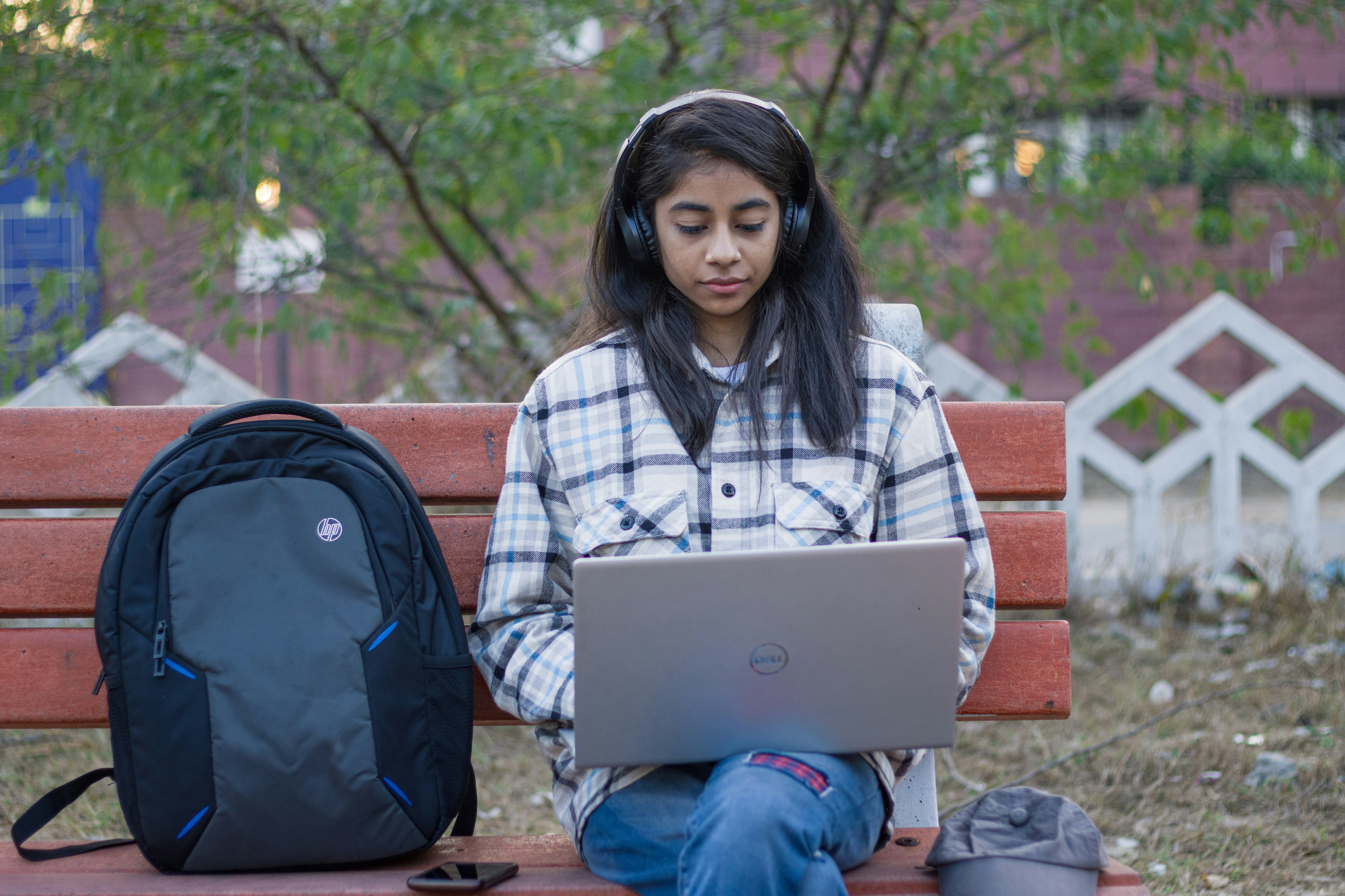 a girl sitting on a bench using a laptop