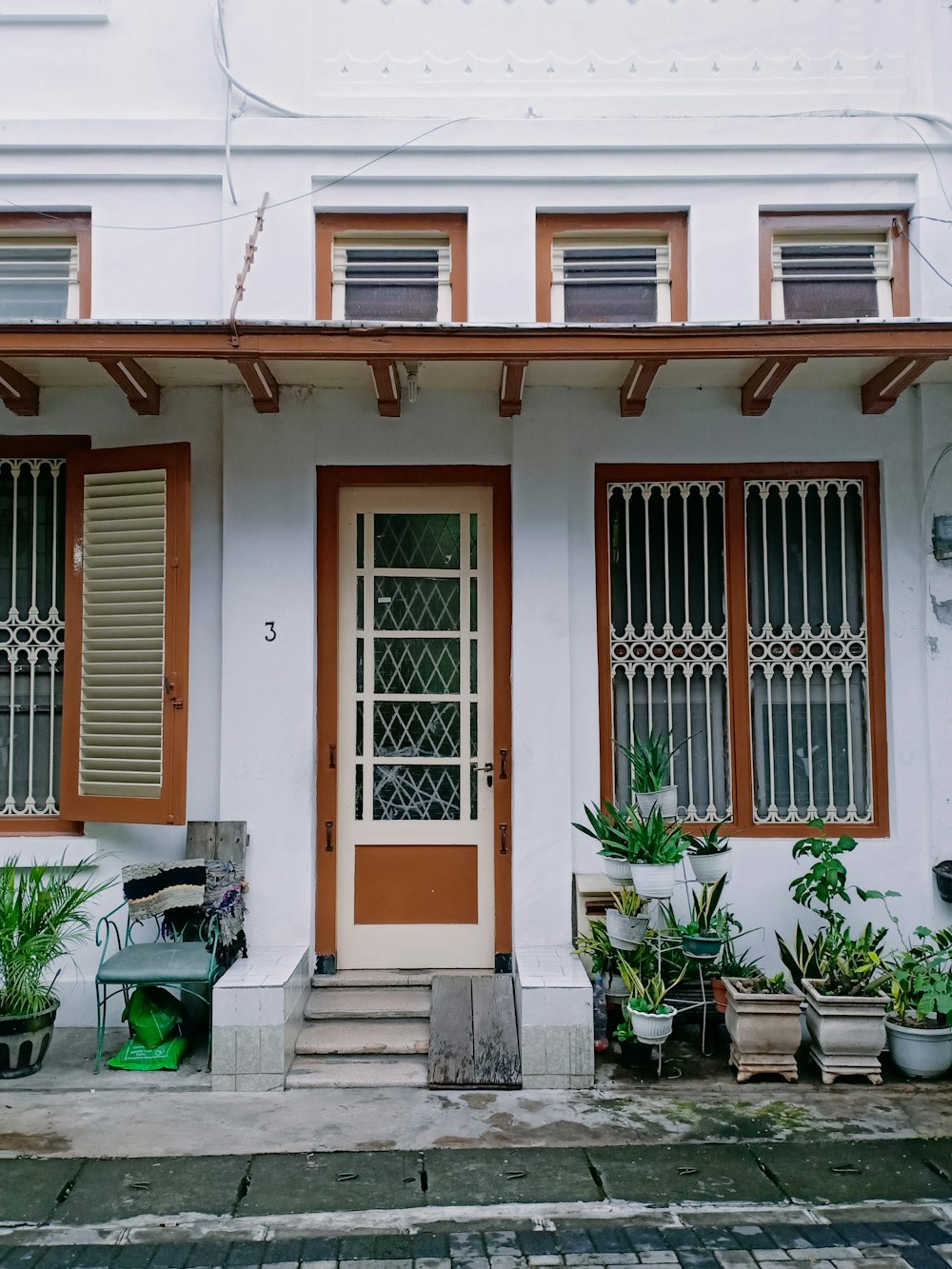 a white house with red shutters and potted plants