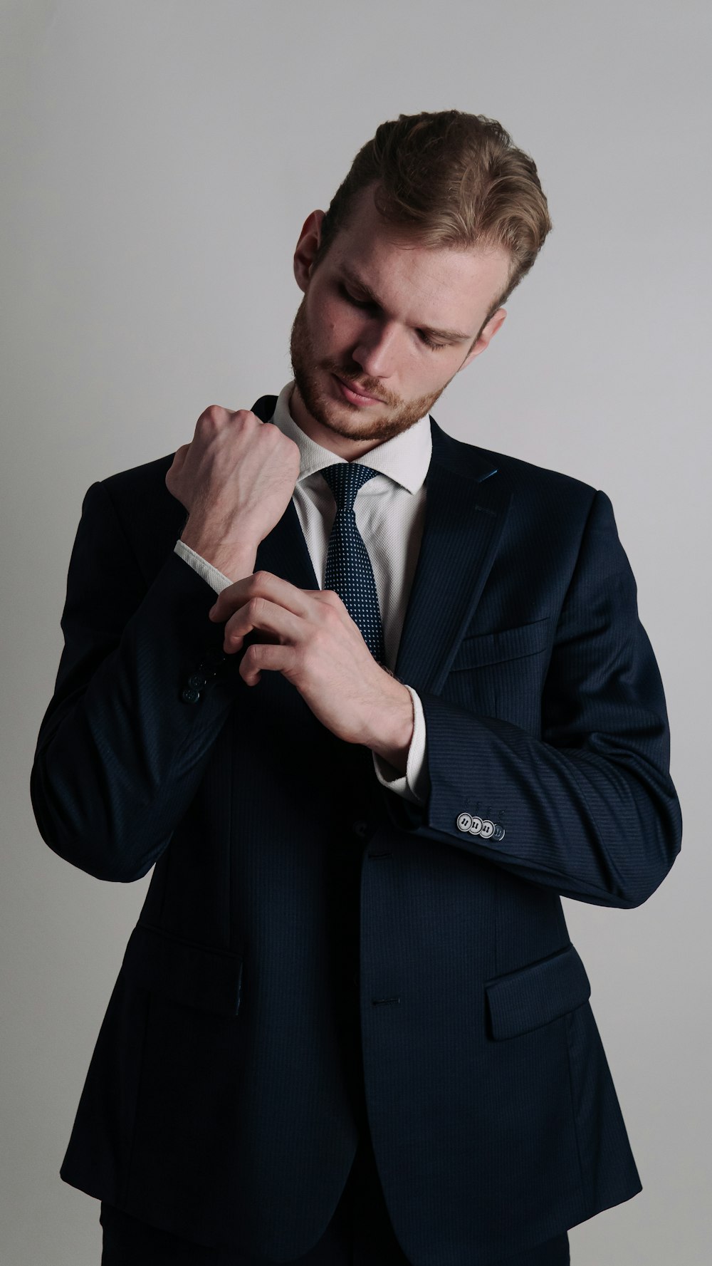 a man in a suit adjusting his tie