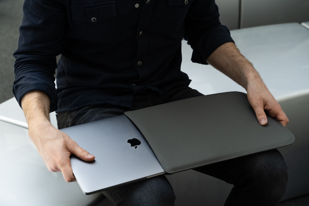 a man sitting on a chair holding an apple laptop