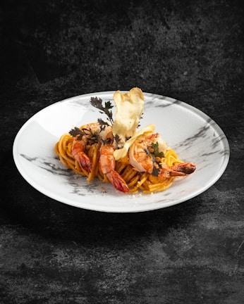 Artfully plated seafood pasta with shrimp and a light, creamy sauce against a navy background.