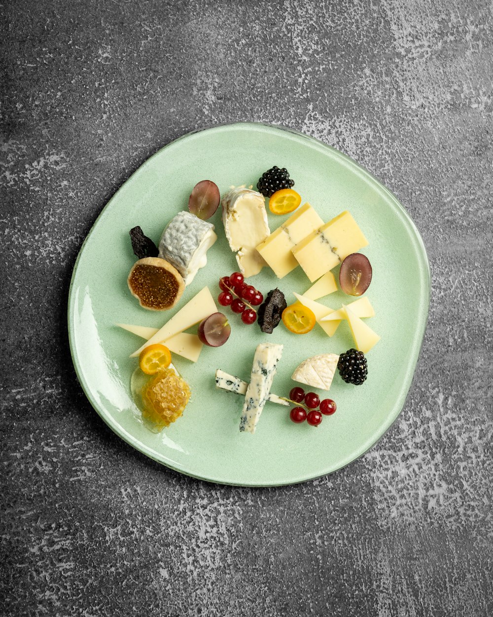 a green plate topped with cheese and fruit