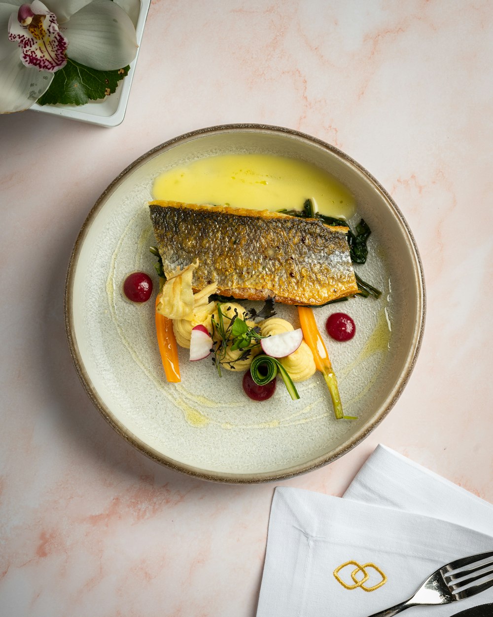 a white plate topped with a fish covered in sauce