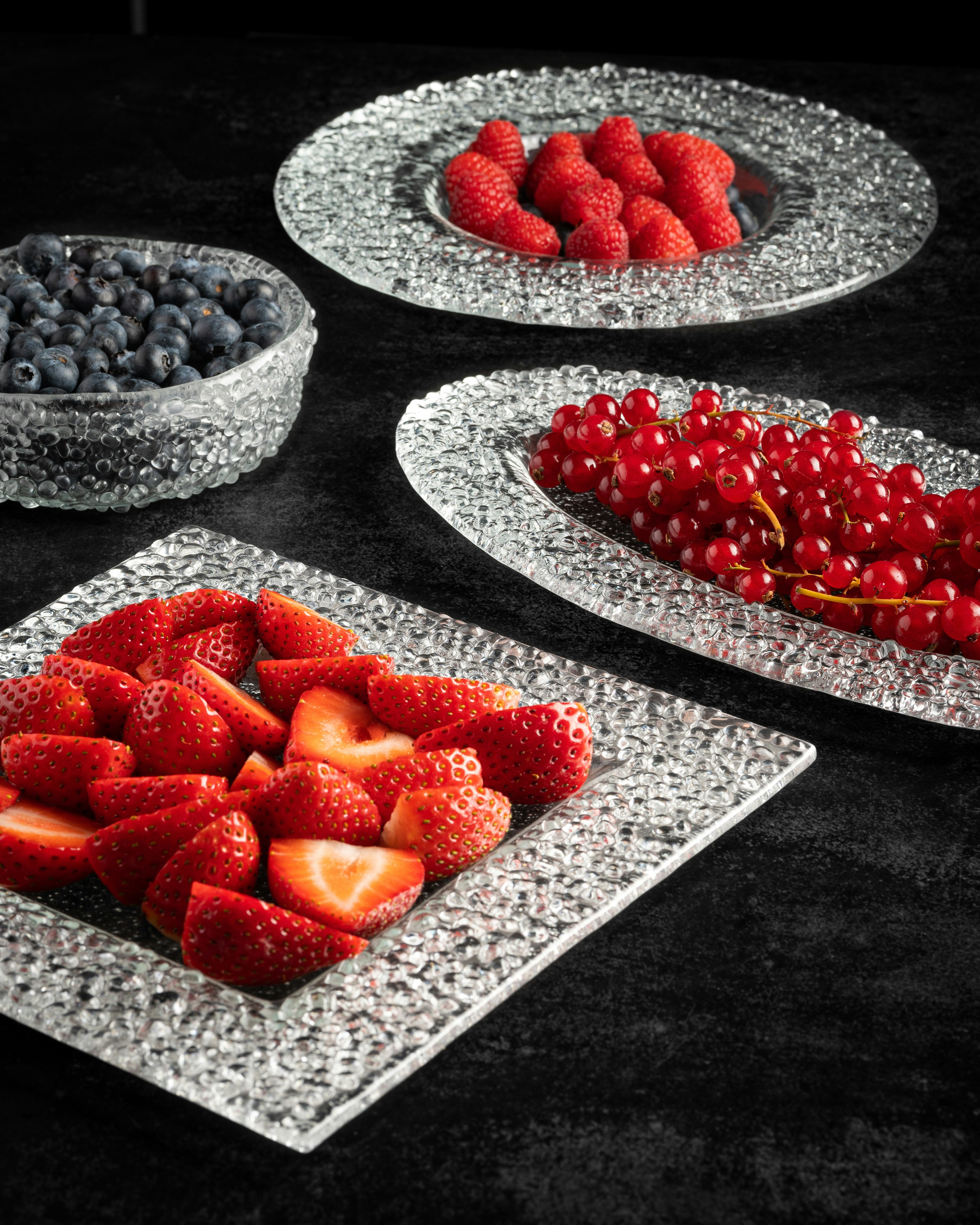 une table surmontée d’assiettes de fruits et de baies