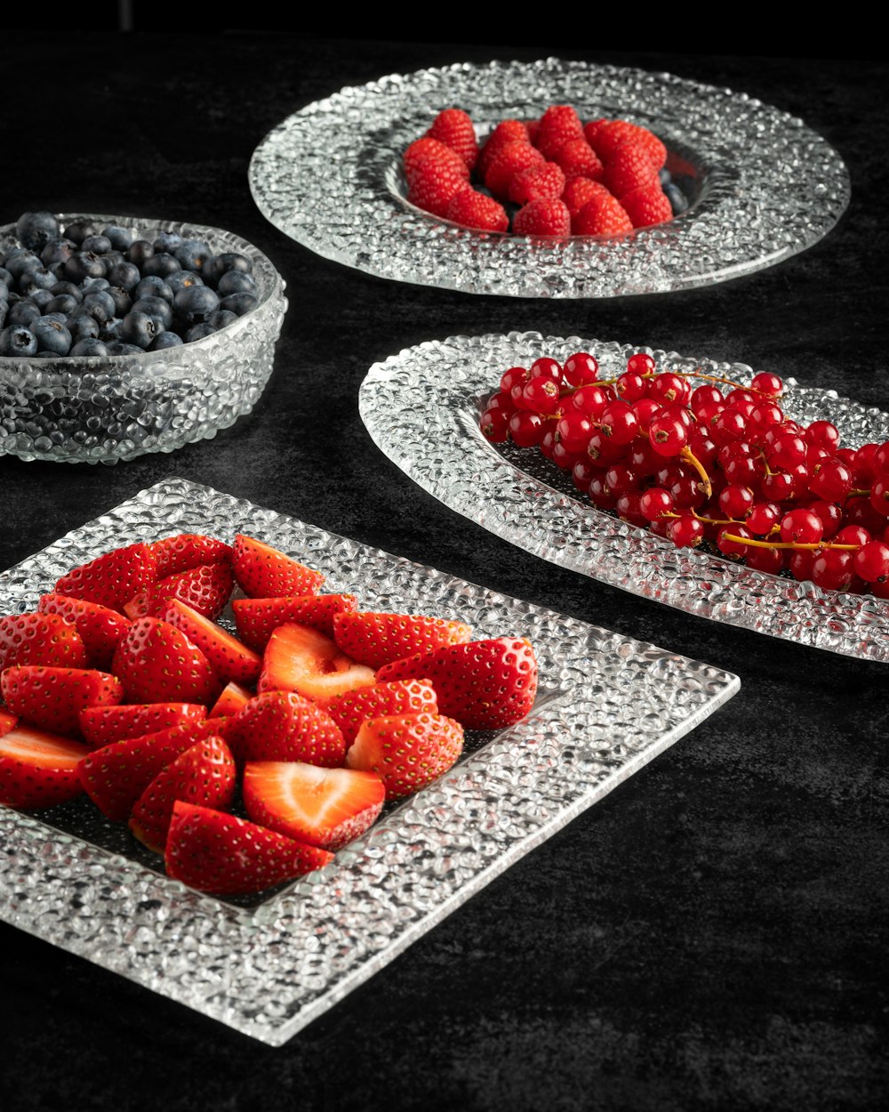 a table topped with plates of fruit and berries