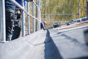 Close-up of a professional inspecting a roof for damage with tools in hand.