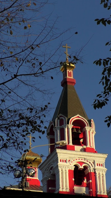 a red and white church steeple with a cross on top