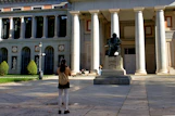 a woman taking a picture of a statue in front of a building