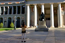 a woman taking a picture of a statue in front of a building
